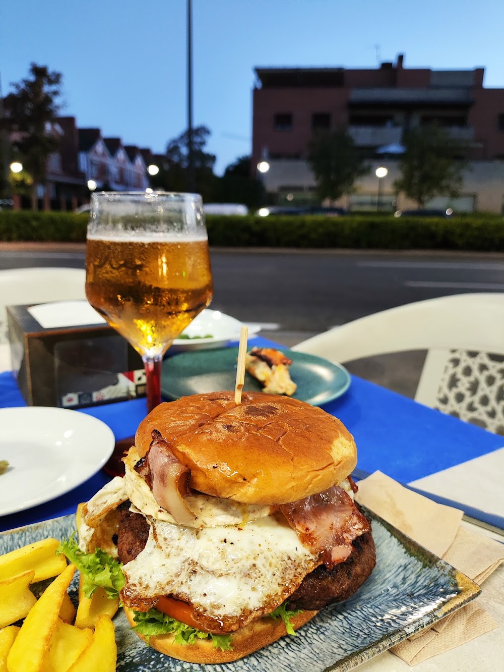 Hamburguesa con huevo frito, bacon y patatas en la terraza de Edén